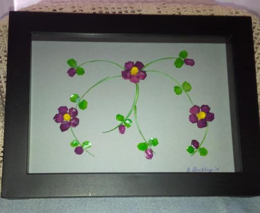 Three delicate purple flowers protected in a shadow box frame